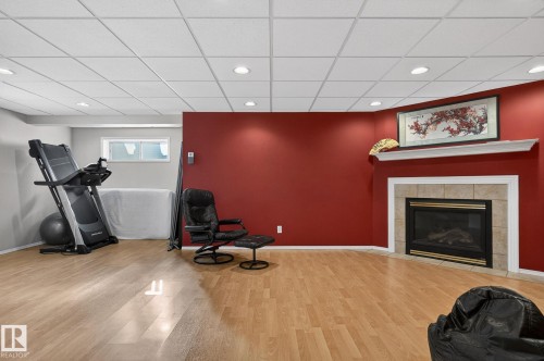 This versatile room features light wood-look flooring, recessed lighting, and a corner fireplace with a tiled surround and mantel - 19 Escada Close, St. Albert, AB - Indoor With Fireplace