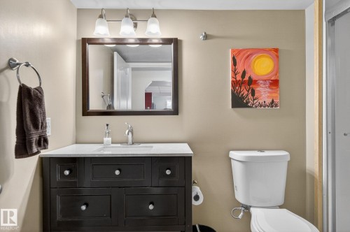 Bathroom featuring a dark wood vanity with a white countertop, a mirror with an overhead light fixture, and a white toilet - 19 Escada Close, St. Albert, AB - Indoor Photo Showing Bathroom