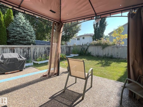 The property features a spacious backyard with a lawn, mature trees, and a wooden fence - 19 Escada Close, St. Albert, AB - Outdoor