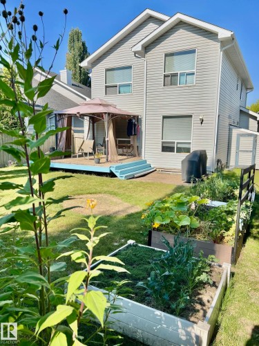 The property features a private backyard with a spacious lawn and raised garden beds - 19 Escada Close, St. Albert, AB - Outdoor With Deck Patio Veranda