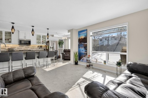 Open concept living space featuring a kitchen with white cabinetry, stainless steel appliances, and a tiled backsplash - 19 Escada Close, St. Albert, AB - Indoor