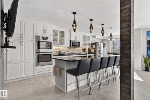 The kitchen features an island with seating, white cabinetry, stainless steel appliances, and pendant lighting - 19 Escada Close, St. Albert, AB - Indoor Photo Showing Kitchen With Upgraded Kitchen