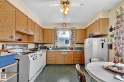 The kitchen features wood cabinetry, a window above the sink, and a white refrigerator - 