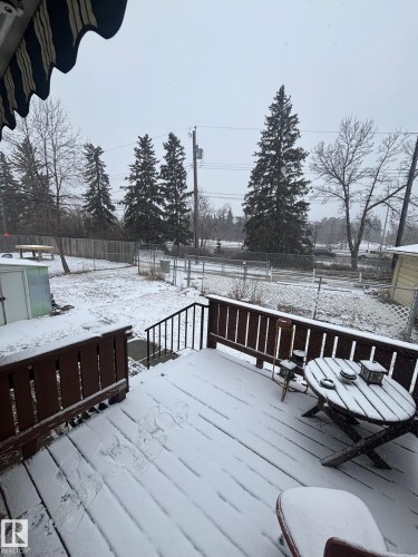 The property features an outdoor deck with wood railings and steps, overlooking a fenced yard - 11255 71 Avenue, Edmonton, AB - Outdoor