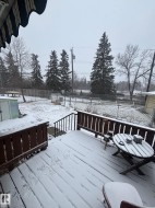The property features an outdoor deck with wood railings and steps, overlooking a fenced yard - 