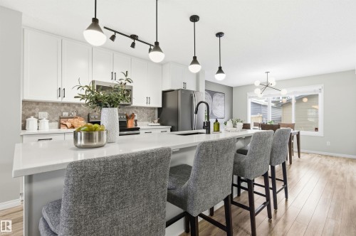 The kitchen features white cabinetry, a light-colored countertop, and a tiled backsplash - 3247 Cherry Crescent, Edmonton, AB - Indoor