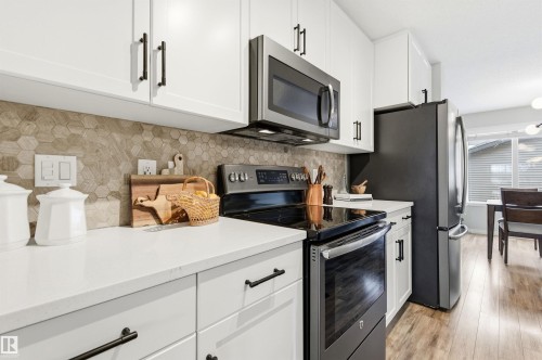 Kitchen featuring white cabinetry, light-colored countertops, a hexagonal tile backsplash, and stainless steel appliances - 3247 Cherry Crescent, Edmonton, AB - Indoor Photo Showing Kitchen With Upgraded Kitchen