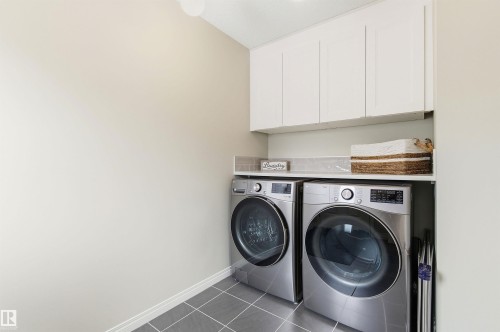 Dedicated laundry area featuring white cabinetry, a light-colored countertop, and grey tile flooring - 3247 Cherry Crescent, Edmonton, AB - Indoor Photo Showing Laundry Room