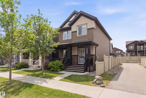The property features a two-story exterior with dark and light brown siding, a front porch with dark railings and steps, and a concrete driveway - 3247 Cherry Crescent, Edmonton, AB - Outdoor With Facade
