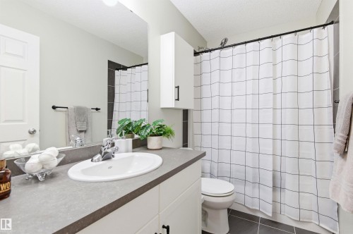 Bathroom featuring a vanity with a countertop and an undermount sink, a mirror, and a shower with a patterned shower curtain - 3247 Cherry Crescent, Edmonton, AB - Indoor Photo Showing Bathroom