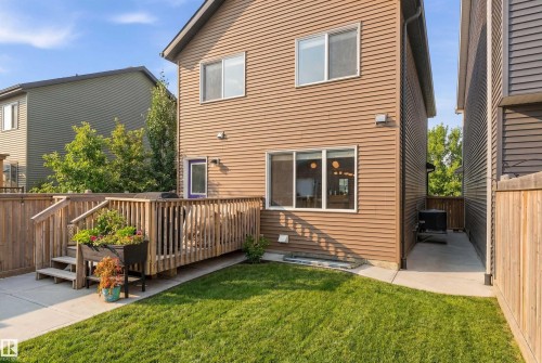 The property features a well-maintained lawn, a wooden deck with railing, and a concrete patio area - 3247 Cherry Crescent, Edmonton, AB - Outdoor With Exterior