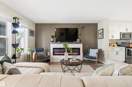 Living area featuring a fireplace with a mantel, a television mounted above, and light-colored walls - 3247 Cherry Crescent, Edmonton, AB - Indoor Photo Showing Living Room With Fireplace