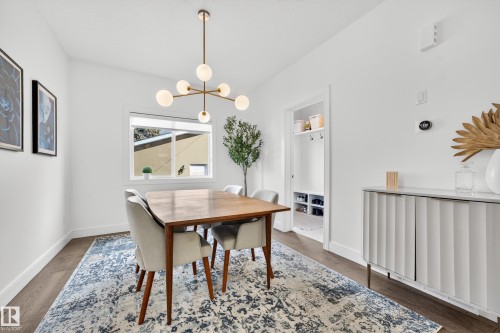 Dining area featuring a modern chandelier, hardwood flooring, and a window providing natural light - 7624 91 Avenue, Edmonton, AB - Indoor Photo Showing Dining Room