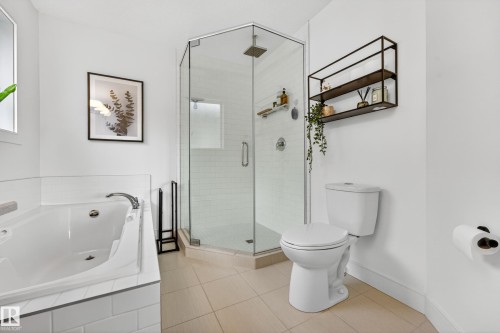 Bathroom featuring a corner glass-enclosed shower, a white soaking tub, and tile flooring - 7624 91 Avenue, Edmonton, AB - Indoor Photo Showing Bathroom