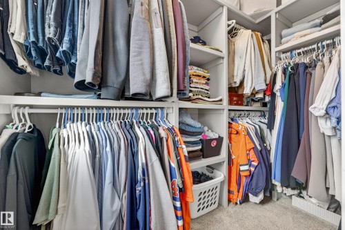 The property features a spacious walk-in closet with built-in shelving, hanging rods, and carpeted flooring - 7624 91 Avenue, Edmonton, AB - Indoor With Storage