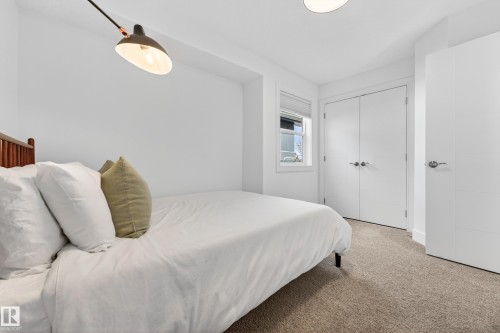 Bedroom featuring a window with blinds, two white doors with silver hardware, a light-colored carpet, and an overhead light fixture - 7624 91 Avenue, Edmonton, AB - Indoor Photo Showing Bedroom