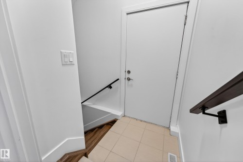 Entryway with a white door, light-colored tile flooring, and a wooden handrail - 7624 91 Avenue, Edmonton, AB - Indoor Photo Showing Other Room