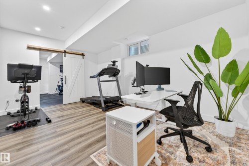 Versatile room featuring light-colored flooring, a white barn door, and recessed lighting - 7624 91 Avenue, Edmonton, AB - Indoor Photo Showing Gym Room
