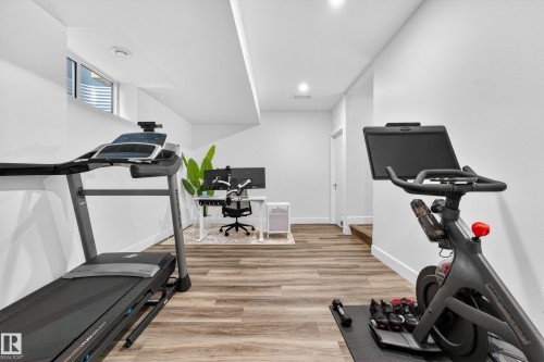This versatile space features light-toned wood flooring, clean white walls, and a recessed window providing natural light - 7624 91 Avenue, Edmonton, AB - Indoor Photo Showing Gym Room
