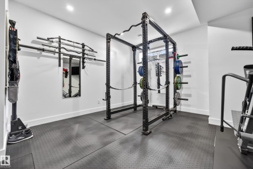 This dedicated fitness space features black rubber flooring, white walls, and recessed lighting - 7624 91 Avenue, Edmonton, AB - Indoor Photo Showing Gym Room
