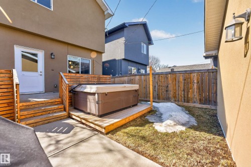 The property features a private yard with a wooden fence and a hot tub on a wooden deck - 7624 91 Avenue, Edmonton, AB - Outdoor With Exterior