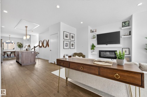 This property features hardwood floors throughout the main living areas - 7624 91 Avenue, Edmonton, AB - Indoor Photo Showing Other Room With Fireplace