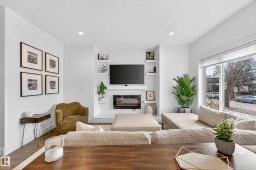 The living area features recessed lighting, hardwood flooring, and a large window providing natural light - 7624 91 Avenue, Edmonton, AB - Indoor Photo Showing Living Room With Fireplace