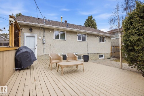 Expansive wood deck with a privacy screen and string lighting, featuring direct access to the stucco exterior - 10222 73 Street, Edmonton, AB 