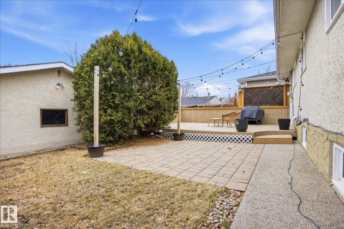 Patio and deck combination featuring string lights, a privacy lattice, and a stucco exterior - 10222 73 Street, Edmonton, AB 