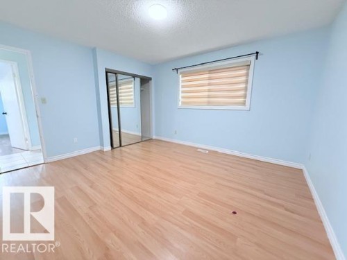 The room features light wood flooring, light blue walls, and a window with blinds - 2831 36 Street, Edmonton, AB - Indoor Photo Showing Other Room