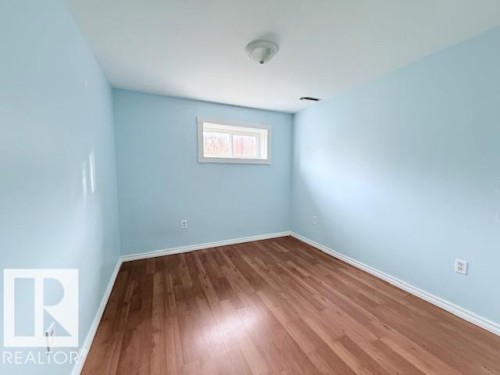 This interior space features light blue walls, wood flooring, and a white-framed window - 2831 36 Street, Edmonton, AB - Indoor Photo Showing Other Room