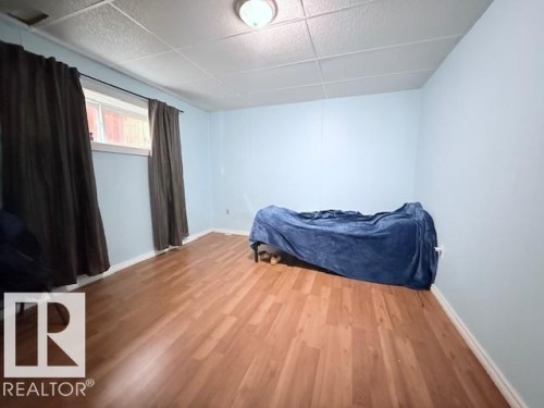 Living area featuring light wood flooring, light blue walls, and a window with dark curtains - 2831 36 Street, Edmonton, AB - Indoor