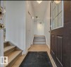 Welcoming entryway with a dark paneled door, light-toned flooring, and a staircase featuring light wooden treads and white risers - 2831 36 Street, Edmonton, AB  - Indoor Photo Showing Other Room 