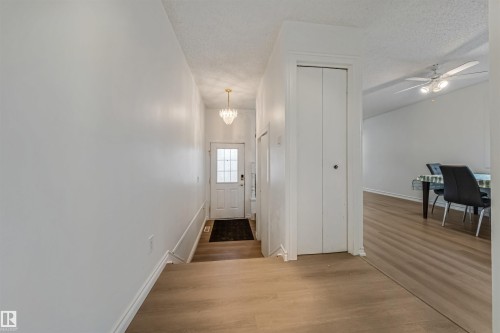 Entryway featuring light-toned flooring, a decorative chandelier, and a white front door with glass inserts - 2831 36 Street, Edmonton, AB - Indoor Photo Showing Other Room