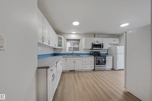 The kitchen features white cabinetry, light-colored flooring, and recessed lighting - 2831 36 Street, Edmonton, AB - Indoor Photo Showing Kitchen
