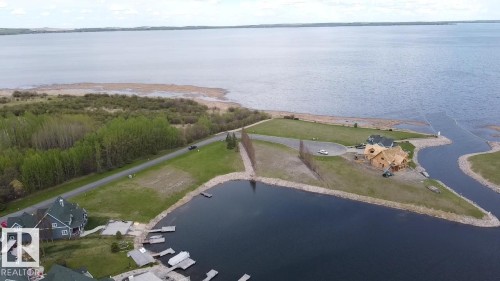 Aerial view showcasing expansive waterfront, mature trees, and nearby properties with private docks - 13 Sunset Harbour, Rural Wetaskiwin County, AB 