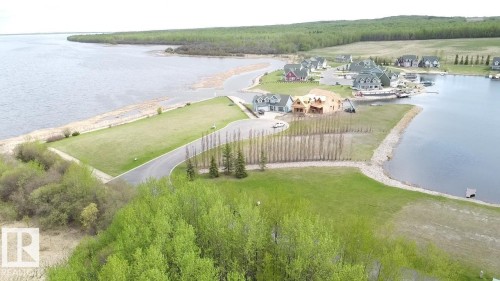 Aerial view showcasing the property's proximity to a body of water and wooded areas - 13 Sunset Harbour, Rural Wetaskiwin County, AB 