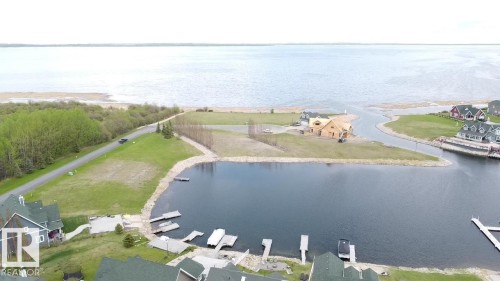 This property features direct access to a tranquil body of water with multiple boat docks visible - 13 Sunset Harbour, Rural Wetaskiwin County, AB 