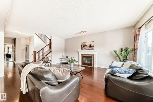 Inviting living area featuring rich hardwood floors, a fireplace with a classic mantel, and a sliding glass door providing natural light - 1330 114B Street, Edmonton, AB - Indoor Photo Showing Living Room With Fireplace