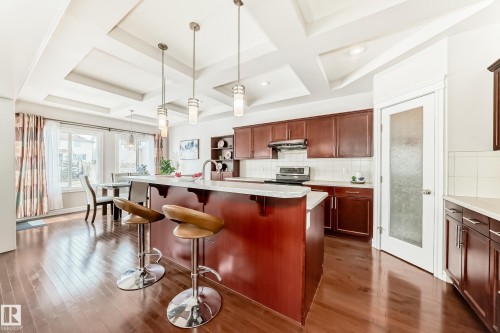 Kitchen featuring rich wood flooring, a central island with bar seating, and recessed lighting in a coffered ceiling - 1330 114B Street, Edmonton, AB - Indoor Photo Showing Kitchen With Upgraded Kitchen