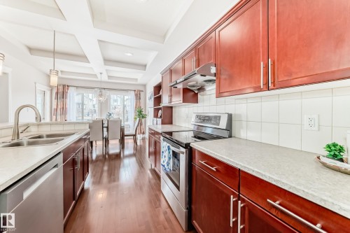 The kitchen features wood cabinetry, light-colored countertops, a double sink with a gooseneck faucet, and a stainless steel oven with an electric cooktop - 1330 114B Street, Edmonton, AB - Indoor Photo Showing Kitchen With Double Sink With Upgraded Kitchen