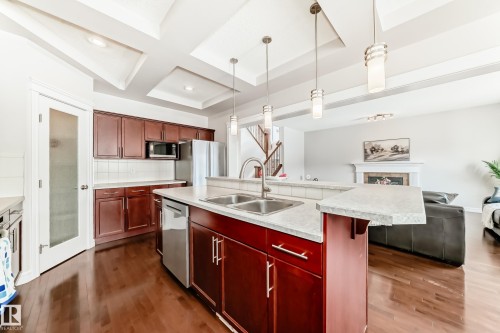 The kitchen features wood cabinetry, stainless steel appliances, and a central island with a double sink - 1330 114B Street, Edmonton, AB - Indoor Photo Showing Kitchen With Double Sink