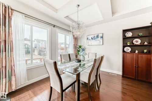 Dining area featuring hardwood floors, a tray ceiling with a chandelier, and large windows providing natural light - 1330 114B Street, Edmonton, AB - Indoor Photo Showing Dining Room