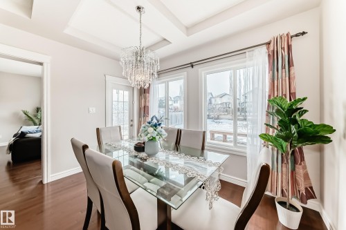 The dining area features hard flooring, a decorative chandelier, and large windows with privacy drapes - 1330 114B Street, Edmonton, AB - Indoor Photo Showing Dining Room