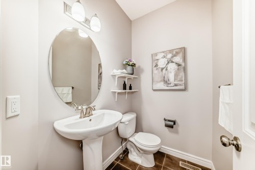 Bathroom featuring a pedestal sink, an oval mirror, and a modern light fixture with three sconces - 1330 114B Street, Edmonton, AB - Indoor Photo Showing Bathroom