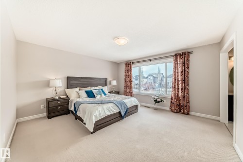 Bedroom featuring neutral-toned carpet, a large window with patterned drapes, and an overhead light fixture - 1330 114B Street, Edmonton, AB - Indoor Photo Showing Bedroom