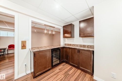 Wet bar featuring dark wood cabinetry, a built-in wine fridge, and a light-colored countertop - 1330 114B Street, Edmonton, AB - Indoor