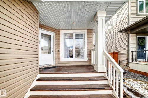 The property features a welcoming front porch with wood flooring and white railings, leading to a white paneled door with decorative glass inserts - 1330 114B Street, Edmonton, AB - Outdoor With Deck Patio Veranda With Exterior
