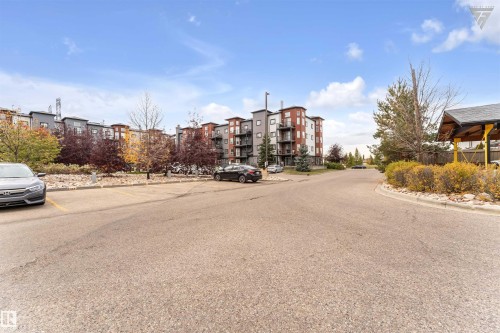 View of the property's exterior, showcasing a multi-story building with balconies and a paved parking area - #418 392 Silver Berry Road Nw, Edmonton, AB - Outdoor