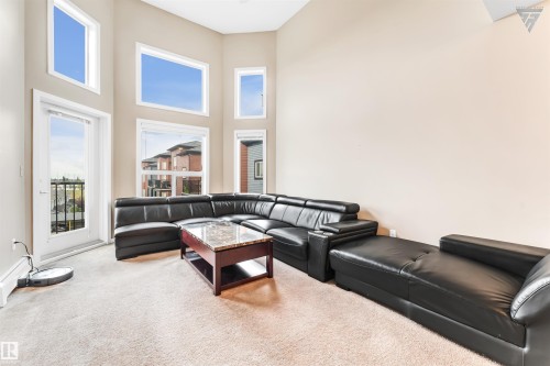 Living area featuring high ceilings, a carpeted floor, and an exterior door leading to a balcony - #418 392 Silver Berry Road Nw, Edmonton, AB - Indoor